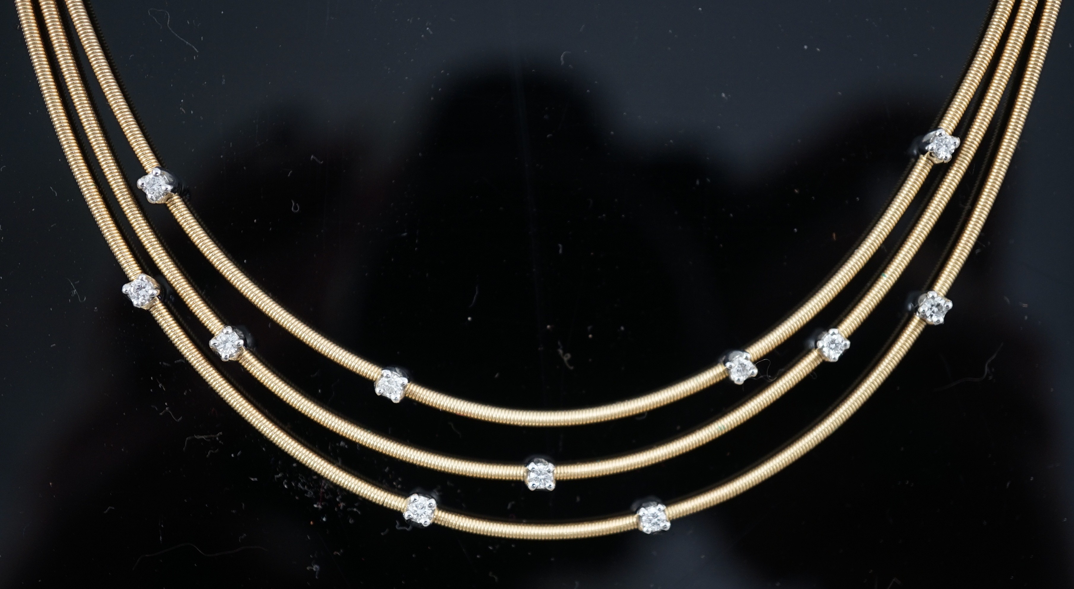 A modern Italian Marco Bicego 18ct gold and eleven stone diamond chip set triple strand necklace